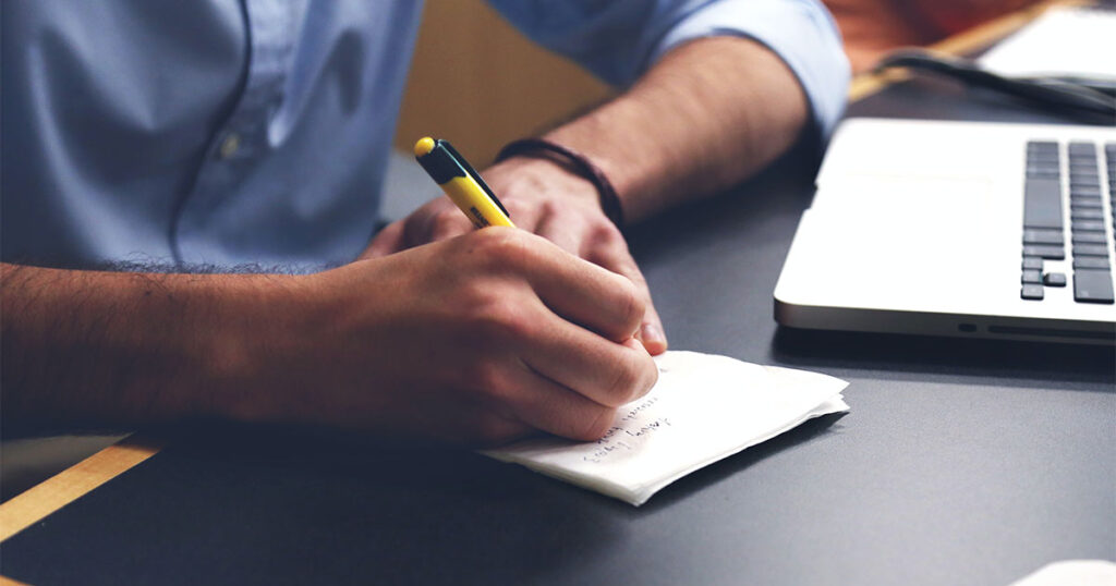 A man focused on writing on paper with a pen, highlighting important considerations when writing.
