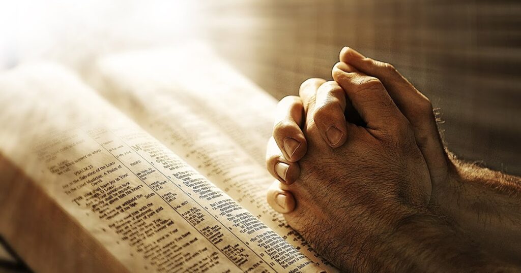 Prayer hands resting on an open Bible, symbolizing devotion and reflection on The Book of Daniel.