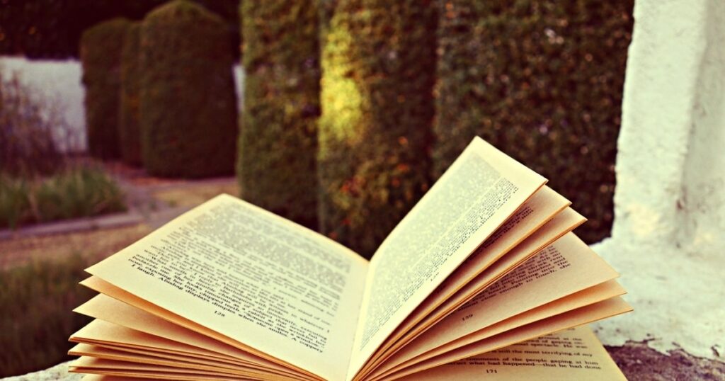 A book rests on a ledge, with a lush garden in the background, illustrating how to establish the main characters of your book.